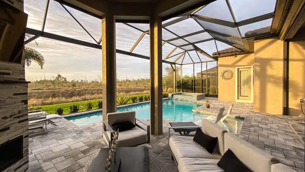 A view of a modern indoor patio with a pool and seating area under a screened enclosure.